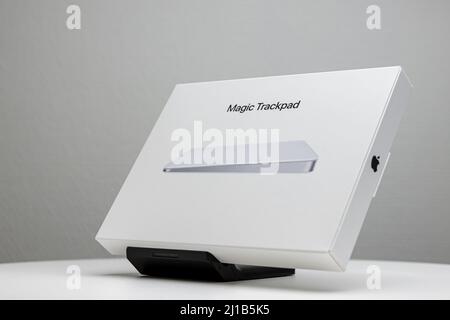 Confezione bianca inclinata del Magic trackpad Mac Apple sul supporto dello schermo. Foto Stock
