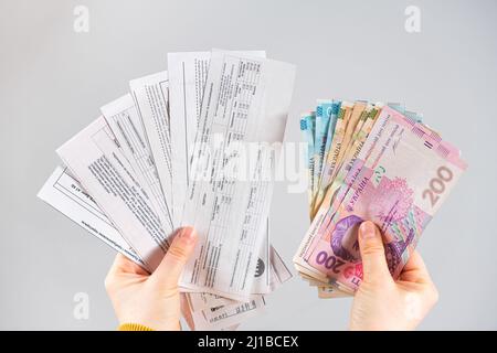Le banconote di hryvnia e i pagamenti per i servizi pubblici sono nelle mani di una persona. Pagamento per gas, elettricità e acqua in Ucraina. Marzo 21, 2022 Foto Stock