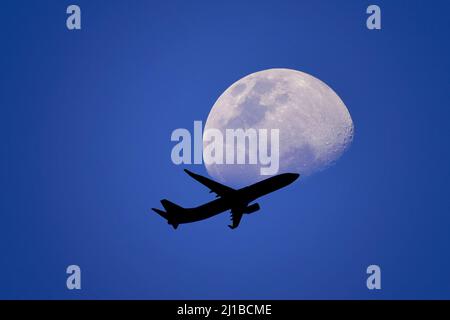 Un aereo che vola attraverso una luna o un aereo passeggeri - il volo passa vicino alla luna. Esplora la nuova frontiera. Concetto di viaggiatore spaziale Foto Stock