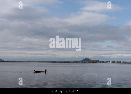 Srinagar, India. 24th Mar 2022. Un uomo fa la sua barca sul lago durante una nuvolosa giornata di primavera a Srinagar. Credit: SOPA Images Limited/Alamy Live News Foto Stock