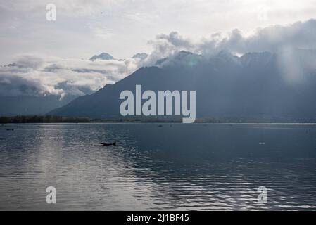 Srinagar, India. 24th Mar 2022. Un uomo fa la sua barca sul lago durante una nuvolosa giornata di primavera a Srinagar. Credit: SOPA Images Limited/Alamy Live News Foto Stock