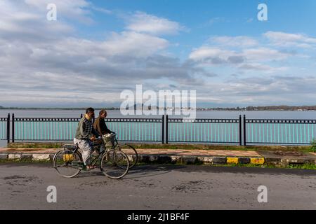 Srinagar, India. 24th Mar 2022. Gli uomini hanno visto andare in bicicletta accanto al lago durante una mattinata nuvolosa a Srinagar. Credit: SOPA Images Limited/Alamy Live News Foto Stock