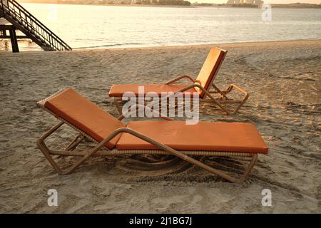 Due lettini arancioni accanto al mare al tramonto serale, Dubai Emirati Arabi Uniti Foto Stock