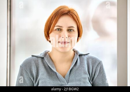 Acconciatura molto corta del bob della giovane donna in polo T-shirt interna. Foto Stock