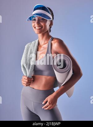 Il più grande piacere della vita è la buona salute. Studio girato di una giovane donna vestita che tiene un asciugamano e tappeto da sforzo su uno sfondo grigio. Foto Stock