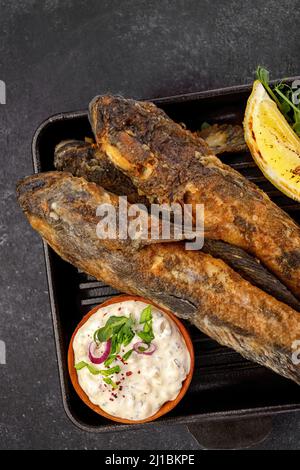 Pesce fritto Gby del Mar Nero, con limone ed erbe, su sfondo scuro Foto Stock