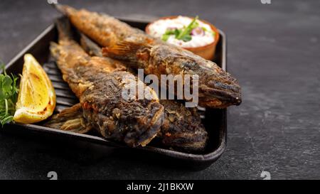 Pesce fritto Gby del Mar Nero, con limone ed erbe, su sfondo scuro Foto Stock