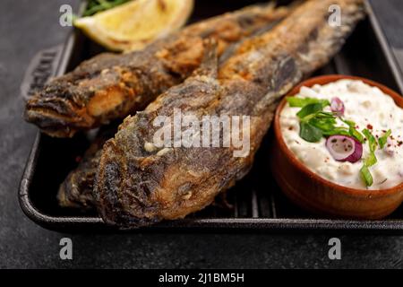 Pesce fritto Gby del Mar Nero, con limone ed erbe, su sfondo scuro Foto Stock