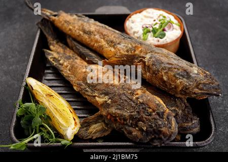 Pesce fritto Gby del Mar Nero, con limone ed erbe, su sfondo scuro Foto Stock