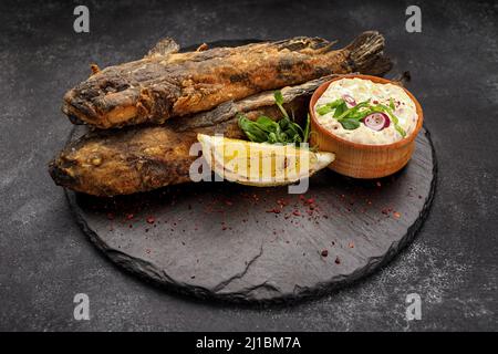 Pesce fritto Gby del Mar Nero, con limone ed erbe, su sfondo scuro Foto Stock