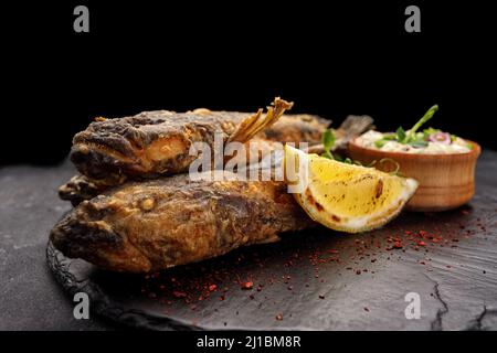 Pesce fritto Gby del Mar Nero, con limone ed erbe, su sfondo scuro Foto Stock