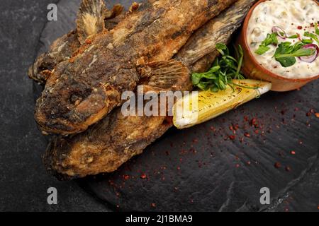 Pesce fritto Gby del Mar Nero, con limone ed erbe, su sfondo scuro Foto Stock