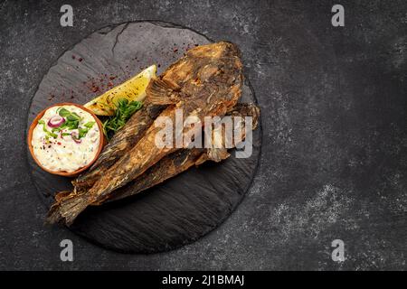 Pesce fritto Gby del Mar Nero, con limone ed erbe, su sfondo scuro Foto Stock