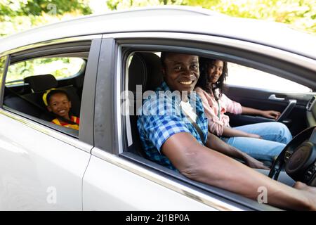 Ritratto di felice famiglia afroamericana con cinture di sicurezza che viaggiano insieme in auto Foto Stock
