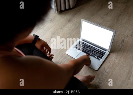 Vista ad alto angolo della donna adulta afroamericana con un computer portatile mentre si esercita a casa Foto Stock
