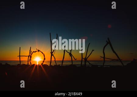 Una foto della parola 'Hokitika' fatta da rami contro il mare Foto Stock