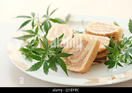 Rotolo dolce con olio di marijuana su piatto bianco. Cucina di cannabis. Disposizione dei deliziosi dessert, vista dall'alto da vicino. Foto Stock