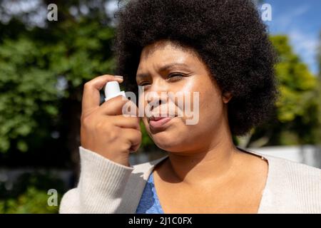 Primo piano della donna di metà adulta afroamericana usando l'inalazione di asma Foto Stock