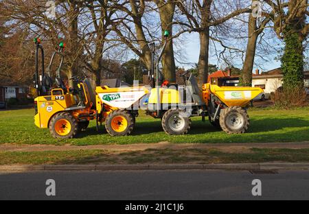 Un paio di dumper gialli parcheggiati off-Road su un piccolo verde in una zona residenziale nel Borough di Hellesdon, Norfolk, Inghilterra, Regno Unito. Foto Stock