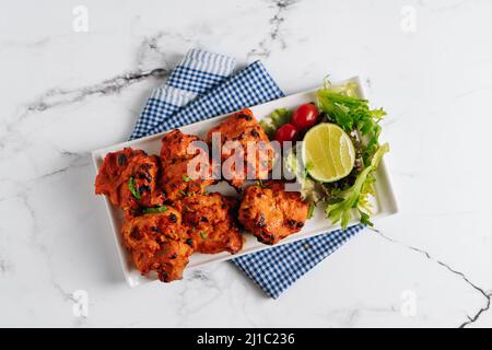 Limone Chili pollo Tikka Boti Kebab in un piatto isolato su tovagliolo vista laterale su sfondo grigio famoso cibo indiano e pakistano Foto Stock