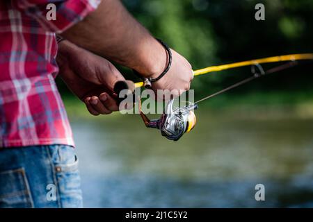 Mulinello da pesca. Canna da pesca con stelo in alluminio. Attrezzi da pesca. Rifornimenti di pesce ed attrezzatura. I pescatori si avvicinano sullo sfondo del fiume Foto Stock