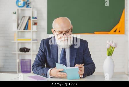 Professore senior a scuola. Insegnante con barba in classe. Foto Stock