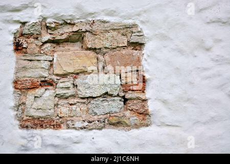 Frammento di muratura vecchia sulla parete bianca intonacata della Chiesa di Giorgio al mercato nella città di Veliky Novgorod. Foto Stock