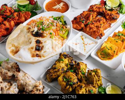 Assortiti famosi indiani e pakistani cibo da tavola verdure biryani, pollo al burro, paneer pollo Tikka boti kebab, lime, Kali Mirchi, salsa di pomodoro, r Foto Stock