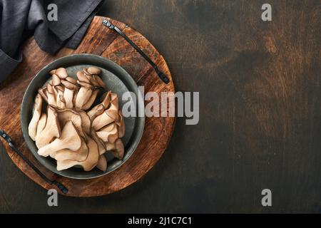 Funghi di ostrica freschi. Stira una vecchia ciotola di deliziosi funghi ostrica biologici su un vecchio sfondo di legno, vista dall'alto con spazio per il testo. Foto Stock