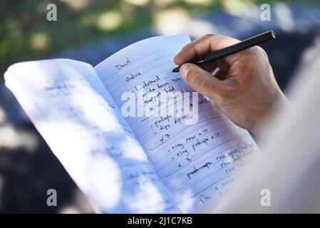Caricamento del piano di esercizio. Girato di un uomo irriconoscibile che scrive nel suo taccuino fuori nel parco. Foto Stock