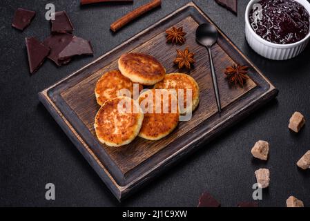 Frittelle di formaggio caserario, sciroppi, frittelle di ricotta su un tagliere di legno. Dolci fatti in casa Foto Stock