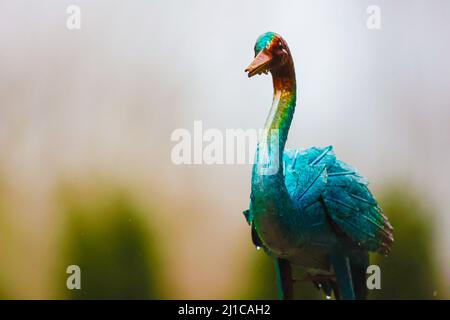 Uno sfondo completamente sfocato della natura con una decorazione in metallo cantiere, un uccello, in primo piano. Foto Stock