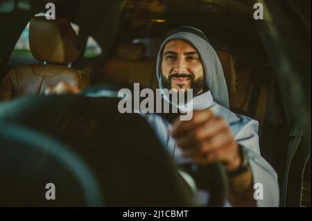 Uomo Saudita che guida una macchina e si sente bene Foto Stock