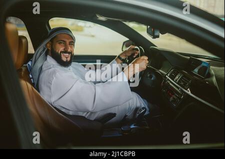 Uomo Saudita che guida una macchina e si sente bene Foto Stock