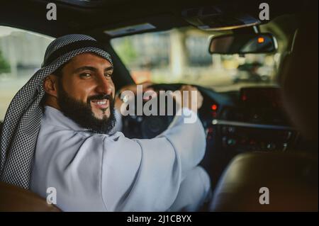 Uomo Saudita che guida una macchina e si sente bene Foto Stock