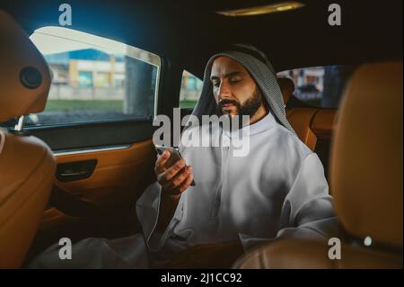 Uomo Saudita seduto in auto e al telefono Foto Stock