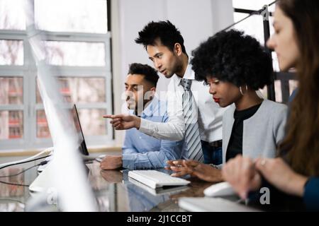 Gruppo di felice la gente di affari con computer portatile a discutere al lavoro in ufficio Foto Stock