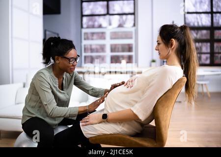 Tranquillo Donna Incinta avente un rilassante massaggio da africani terapista femmina a casa Foto Stock