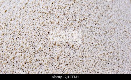 Granulo secondario in polipropilene, pellet di plastica bianco sbriciolano al tavolo. Materie prime plastiche in granuli per l'industria. Resina polimerica Foto Stock