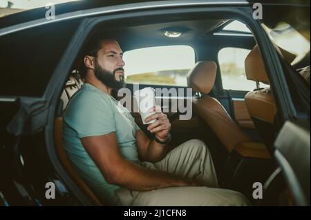 Un giovane con una tazza di caffè seduta in un'auto Foto Stock