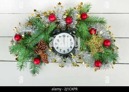 Ornamento di Natale o di Capodanno. Corona di Natale di rami di abete, orologi e palle luminose. Foto Stock