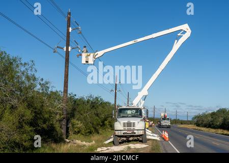 Un operatore di costruzioni elettriche o un lineman che lavora in una benna rialzata per eseguire nuove linee di trasmissione elettrica. Foto Stock