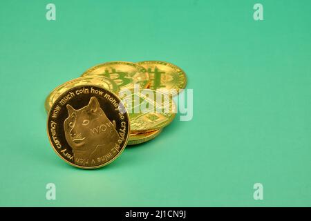 Vista orizzontale dei token di criptovaluta, come dogecoina, bitcoin, litecoina ed eterero con sfondo verde. Foto Stock