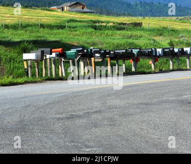 Una lunga fila di caselle postali attende la consegna postale in questa strada di campagna nel Montana rurale. Foto Stock