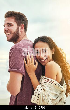 HES tutto ciò di cui avete bisogno. Scatto corto di una giovane coppia affettuosa godendo il loro tempo sulla spiaggia. Foto Stock