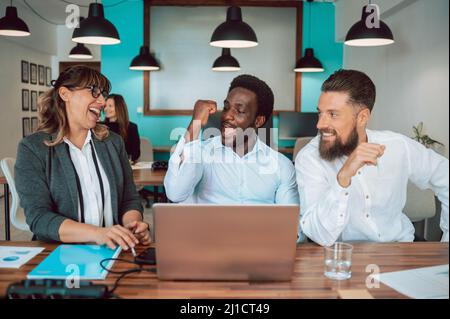 Allegri colleghi multietnici al tavolo Foto Stock