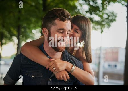 Hanno sempre un tempo meraviglioso insieme. Scatto corto di una giovane donna attraente che abbraccia il suo ragazzo da dietro mentre in una data. Foto Stock