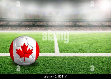 Football in uno stadio all'aperto luminoso con bandiera del Canada dipinta. Mettere a fuoco su primo piano e palla di calcio con profondità di campo poco profonda su sfondo AN Foto Stock