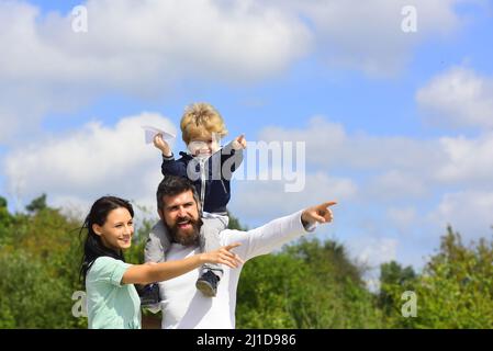 Bambino che gioca con l'aeroplano giocattolo e sognando futuro, concetto di sogni e viaggi. Buon ritratto di famiglia divertirsi insieme al giocattolo carta aereo Foto Stock