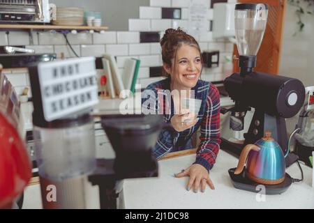 Un barista sorridente che tiene una tazza di caffè in un caffè Foto Stock